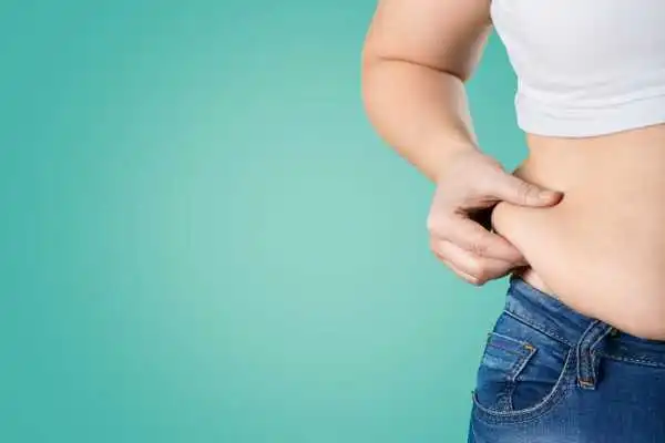 Image of woman pinching her love handles to show weight gain Middlesex